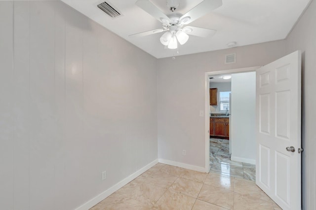 empty room with ceiling fan, marble finish floor, visible vents, and baseboards