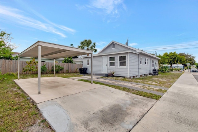 exterior space with a front yard, fence, cooling unit, and concrete driveway