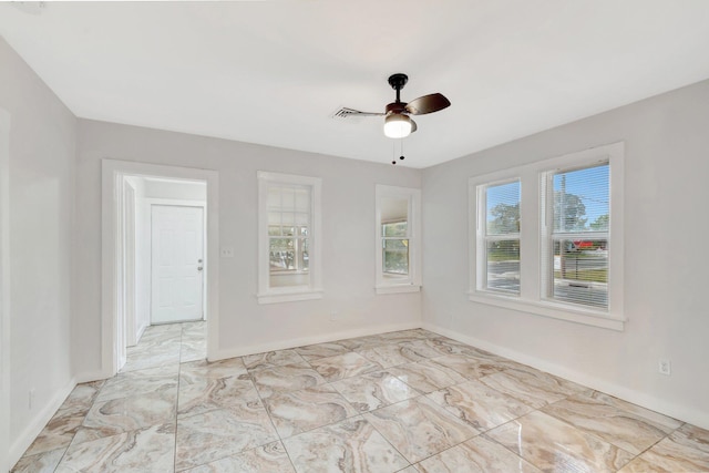 empty room with marble finish floor, ceiling fan, and baseboards