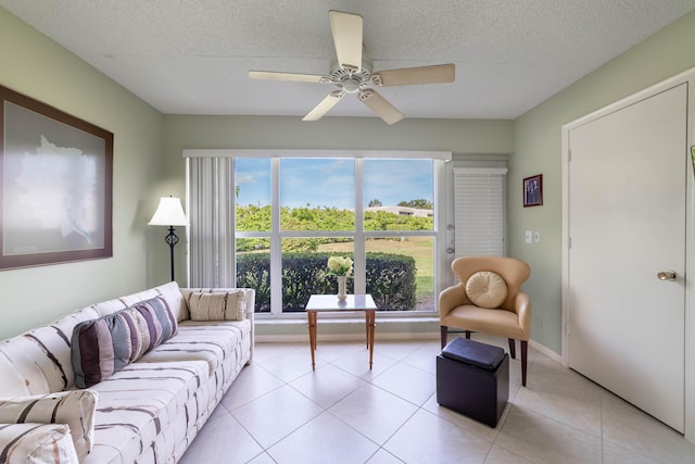 living area featuring a ceiling fan, light tile patterned flooring, and a textured ceiling