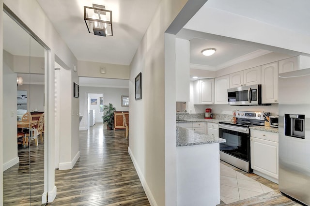 kitchen with crown molding, light hardwood / wood-style flooring, stainless steel appliances, light stone countertops, and white cabinets