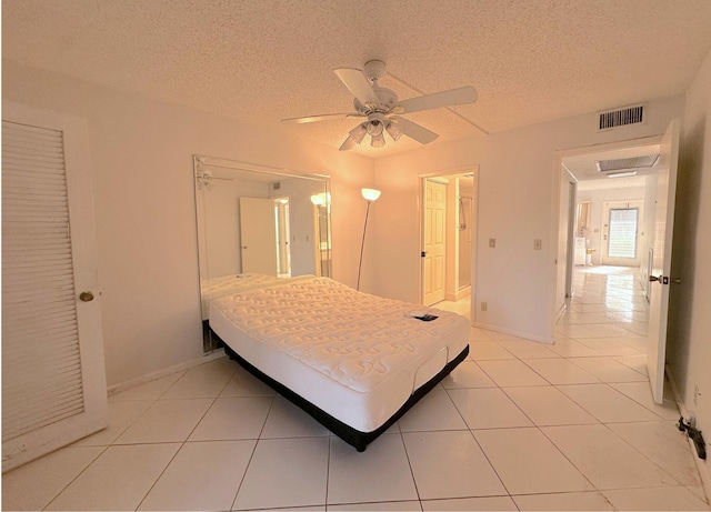 bedroom featuring ceiling fan, tile patterned floors, and a textured ceiling