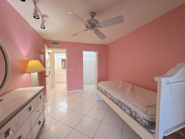 bedroom with ceiling fan, track lighting, a textured ceiling, light tile patterned flooring, and a spacious closet