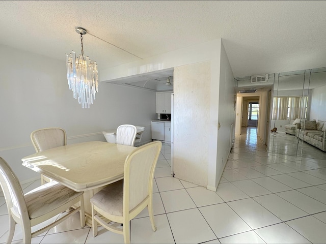 dining space with a notable chandelier, a textured ceiling, and light tile patterned floors