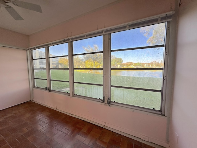 unfurnished sunroom featuring a water view and ceiling fan