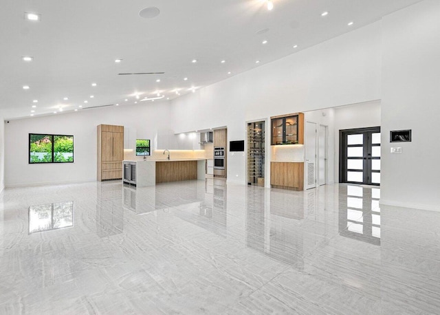 unfurnished living room featuring sink and high vaulted ceiling