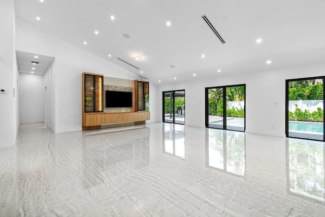 unfurnished living room with plenty of natural light and high vaulted ceiling