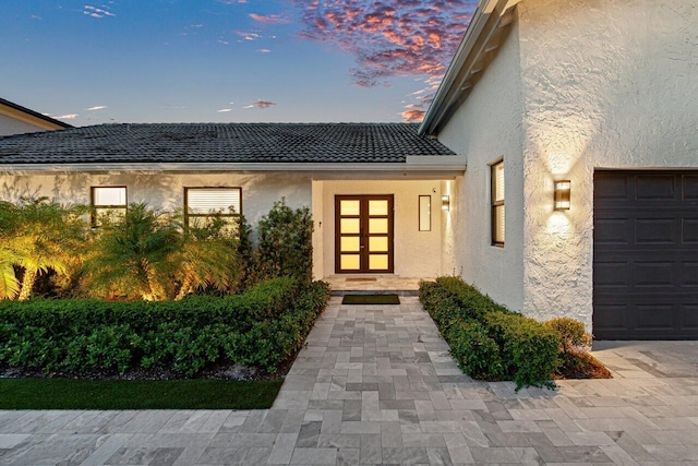 exterior entry at dusk featuring a garage