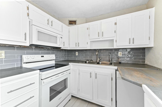 kitchen with white appliances, white cabinetry, and sink