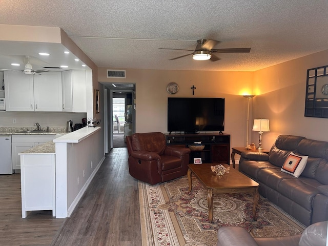 living room with ceiling fan, sink, dark hardwood / wood-style floors, and a textured ceiling