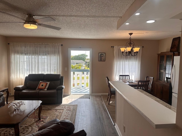 living room featuring dark hardwood / wood-style flooring, a textured ceiling, and ceiling fan with notable chandelier