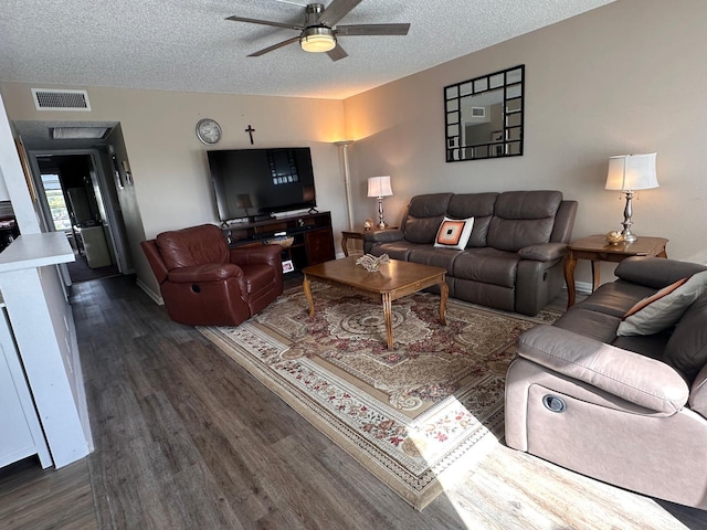 living room featuring ceiling fan, dark wood-type flooring, and a textured ceiling