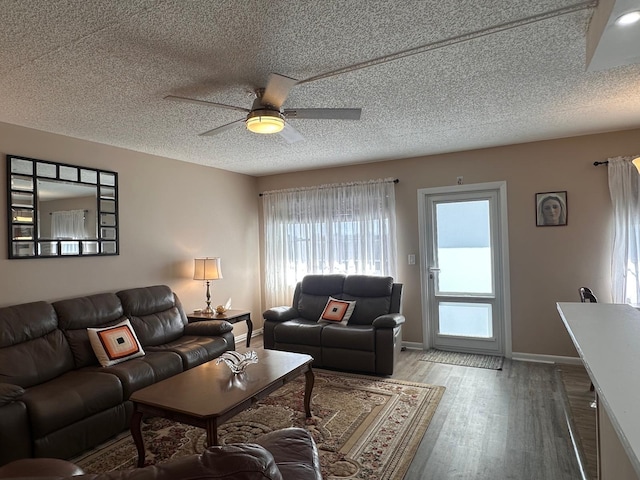 living room featuring hardwood / wood-style flooring, ceiling fan, and a textured ceiling