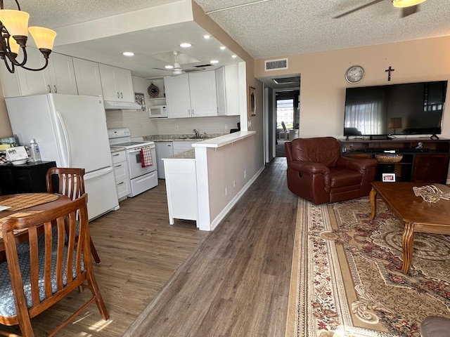 kitchen with kitchen peninsula, white appliances, ceiling fan, dark wood-type flooring, and white cabinets