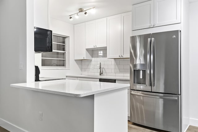 kitchen featuring stainless steel fridge with ice dispenser, sink, light stone counters, white cabinets, and decorative backsplash