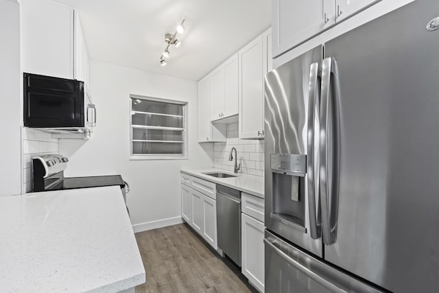 kitchen with white cabinetry, stainless steel appliances, light hardwood / wood-style floors, sink, and tasteful backsplash