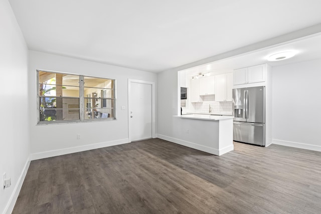 kitchen with stainless steel fridge with ice dispenser, dark wood-type flooring, kitchen peninsula, white cabinets, and tasteful backsplash