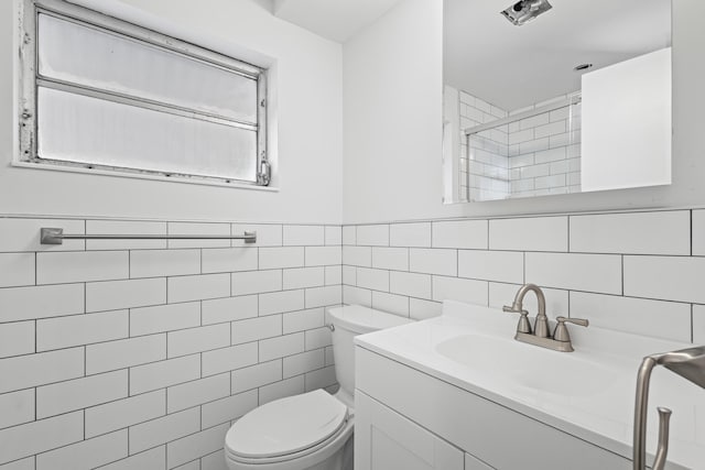 bathroom with tile walls, vanity, toilet, and a shower