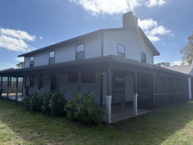 rear view of property featuring a sunroom and a lawn