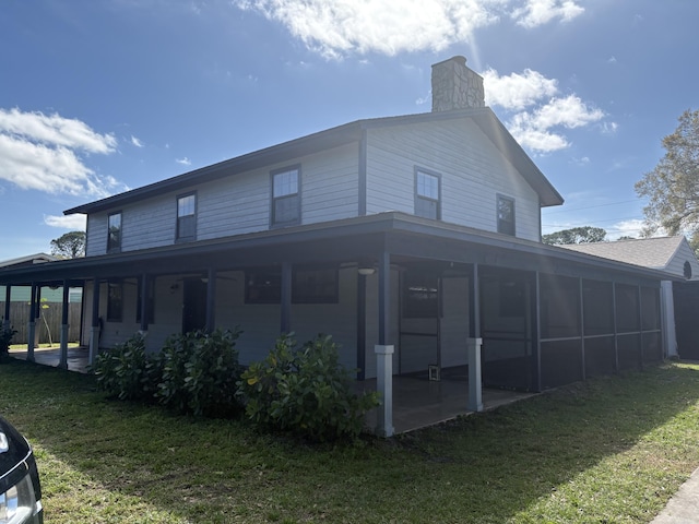 view of side of home featuring a patio area, a sunroom, and a lawn