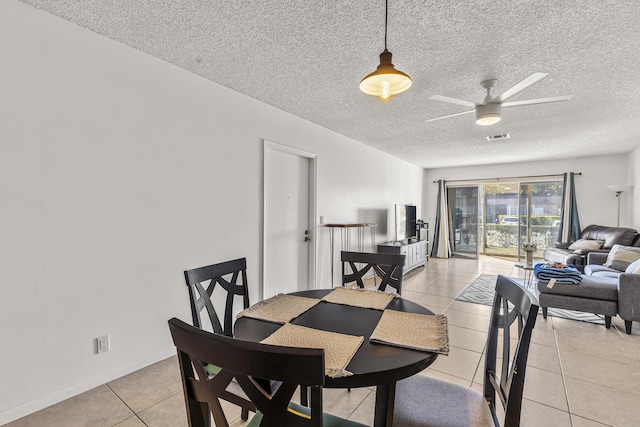 dining room with light tile patterned floors, visible vents, baseboards, ceiling fan, and a textured ceiling