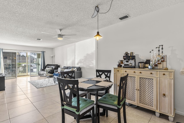 dining area featuring a ceiling fan, visible vents, a textured ceiling, and light tile patterned flooring