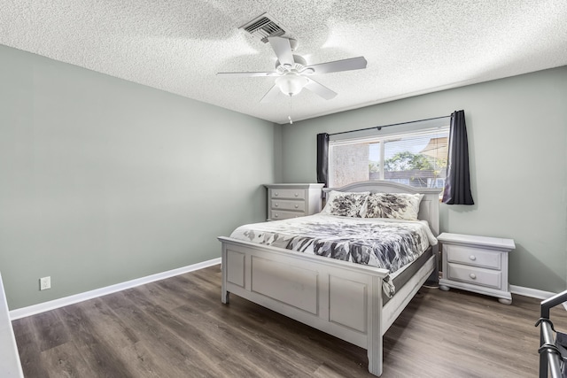 bedroom featuring visible vents, a textured ceiling, baseboards, and dark wood-type flooring