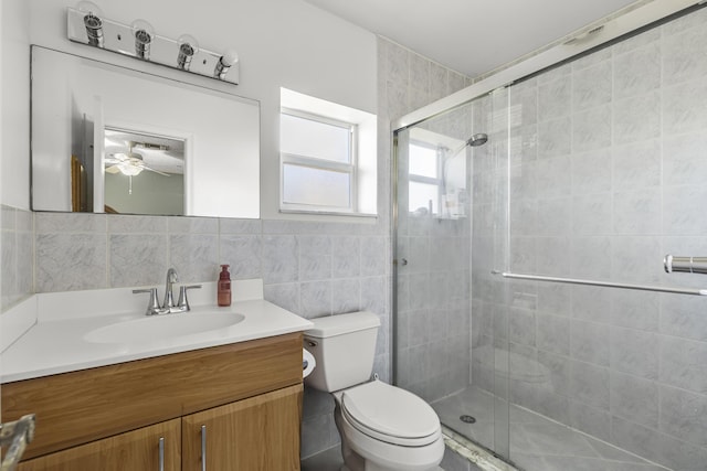 bathroom featuring toilet, vanity, tile walls, and a shower stall