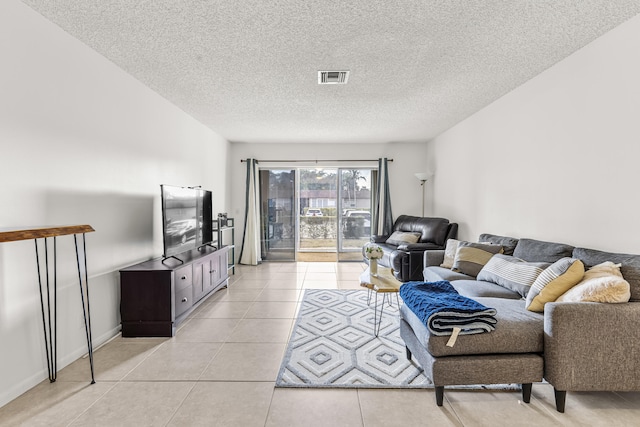 living room with a textured ceiling, light tile patterned flooring, and visible vents