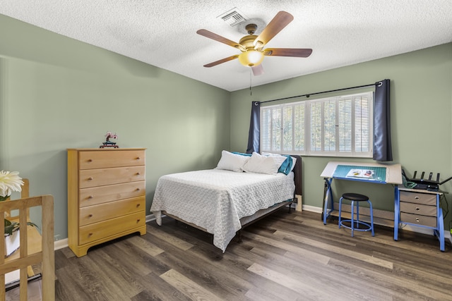 bedroom with baseboards, visible vents, a ceiling fan, dark wood-type flooring, and a textured ceiling