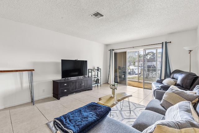 living room featuring light tile patterned floors, a textured ceiling, and visible vents