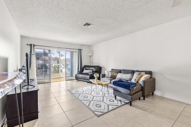 living area with visible vents, a textured ceiling, baseboards, and light tile patterned flooring