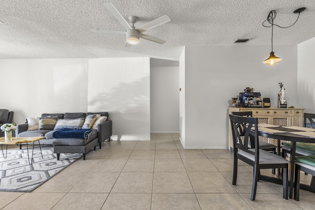 living room featuring light tile patterned floors, visible vents, ceiling fan, a textured ceiling, and baseboards