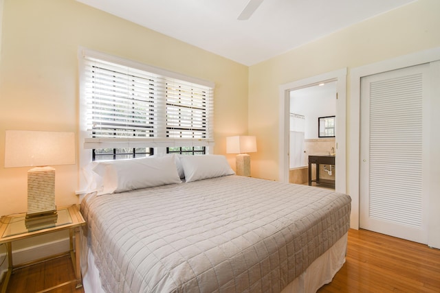 bedroom with a ceiling fan, ensuite bath, a closet, and wood finished floors