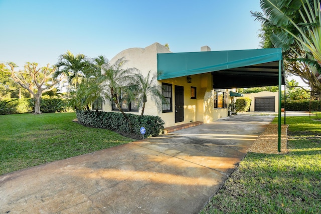 view of front of house with an outbuilding, driveway, stucco siding, and a front lawn
