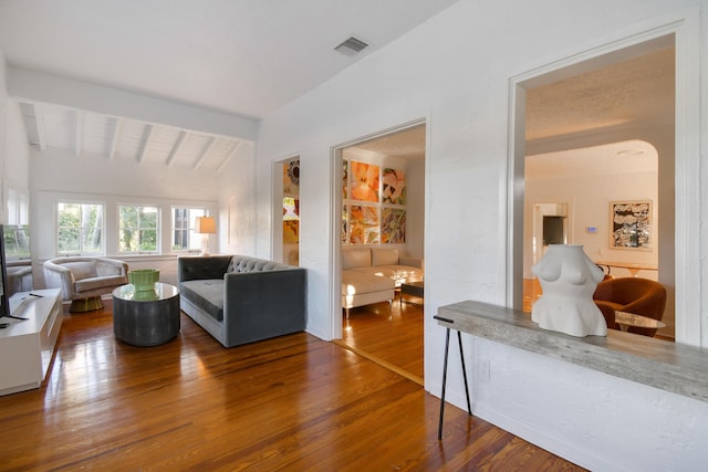 living area with vaulted ceiling with beams, visible vents, and wood finished floors