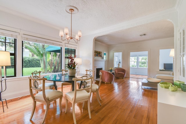 dining space featuring visible vents, crown molding, a fireplace, and light wood-type flooring