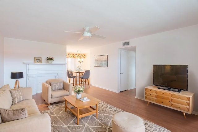 living room featuring a ceiling fan, baseboards, visible vents, and wood finished floors