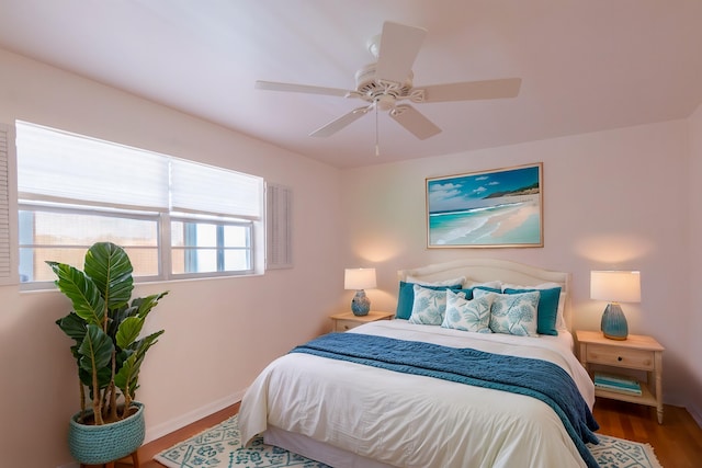 bedroom featuring ceiling fan, baseboards, and wood finished floors