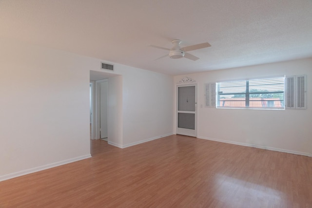 unfurnished room featuring light wood finished floors, visible vents, baseboards, and a ceiling fan
