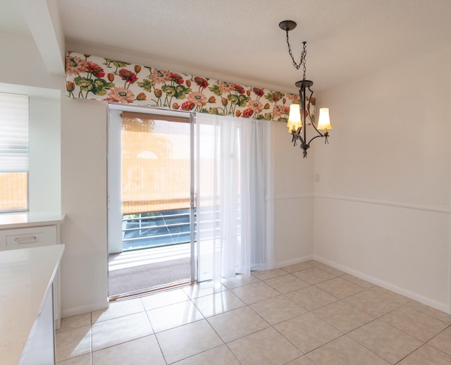 unfurnished dining area with a chandelier, baseboards, and light tile patterned floors