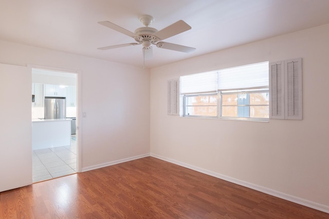 empty room featuring wood finished floors, baseboards, and ceiling fan