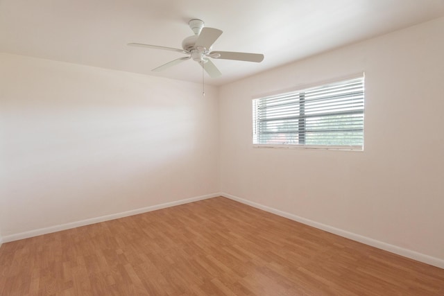 spare room with baseboards, light wood-style flooring, and ceiling fan