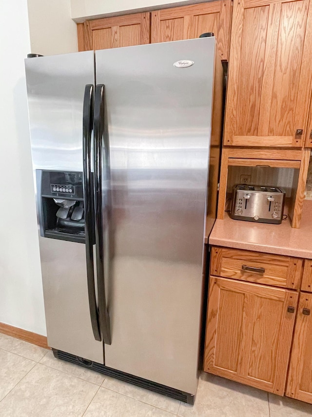 kitchen featuring stainless steel fridge with ice dispenser and light tile patterned flooring