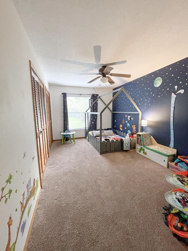 bedroom with a textured ceiling, a closet, ceiling fan, and carpet