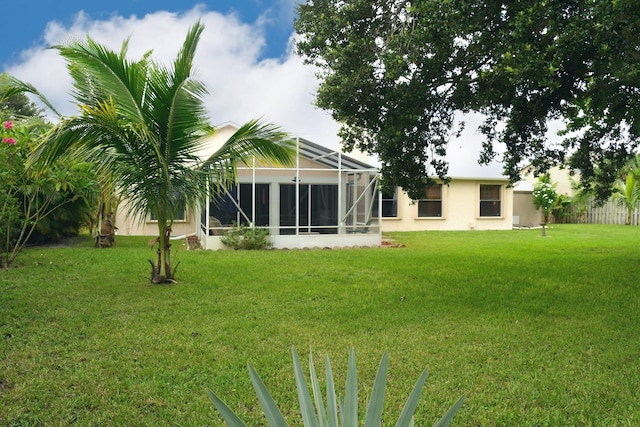 back of house with a yard and glass enclosure