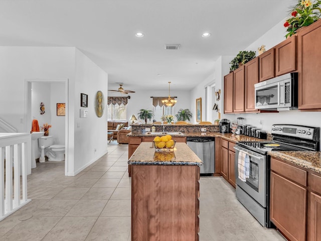 kitchen featuring stainless steel appliances, a center island, kitchen peninsula, and dark stone countertops