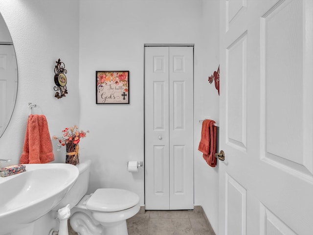 bathroom with toilet, tile patterned flooring, and sink