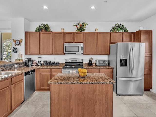 kitchen featuring a kitchen island, light tile patterned flooring, appliances with stainless steel finishes, and dark stone counters