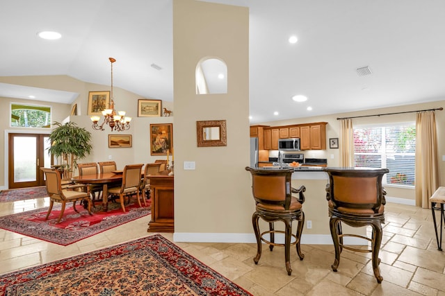 kitchen featuring high vaulted ceiling, a chandelier, a kitchen bar, hanging light fixtures, and stainless steel appliances